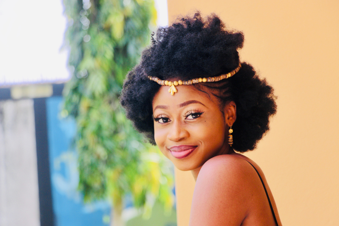 Cheerful black woman with curly hair and ethnic accessories