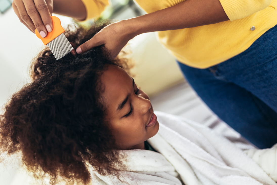 Mother doing head lice cleaning on her daughter hair